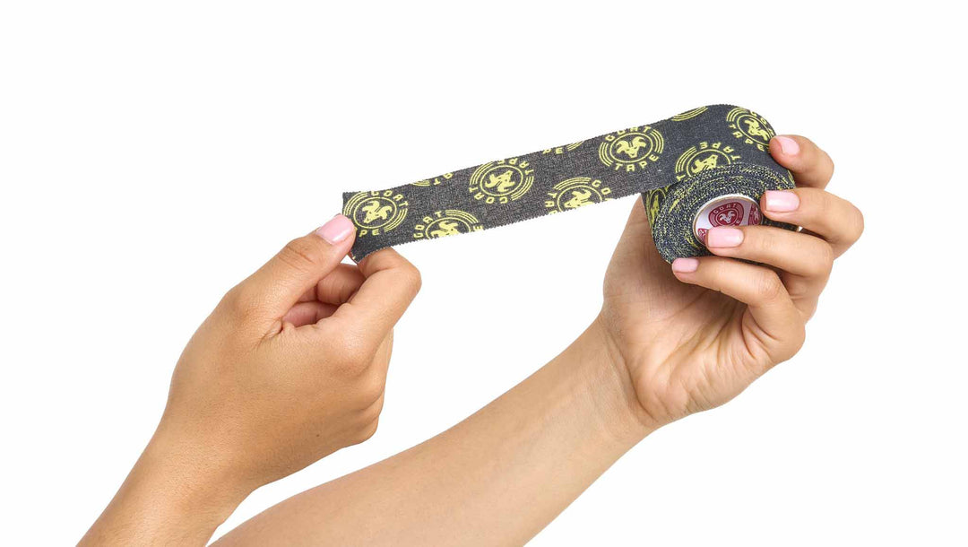 Hands stretching black and yellow Goat Tape from a roll