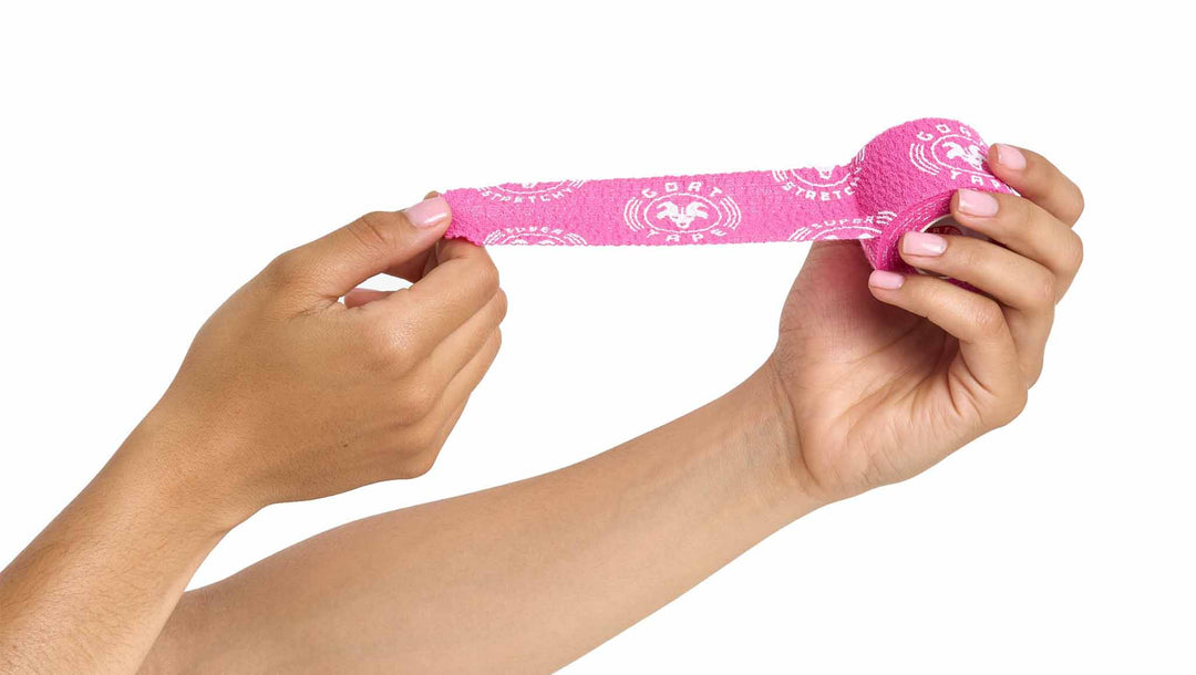 Hands stretching pink Goat Tape from a roll